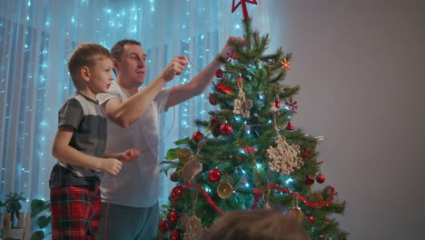 Father-and-two-sons-decorate-Christmas-tree-together.-High-quality-4k-footage